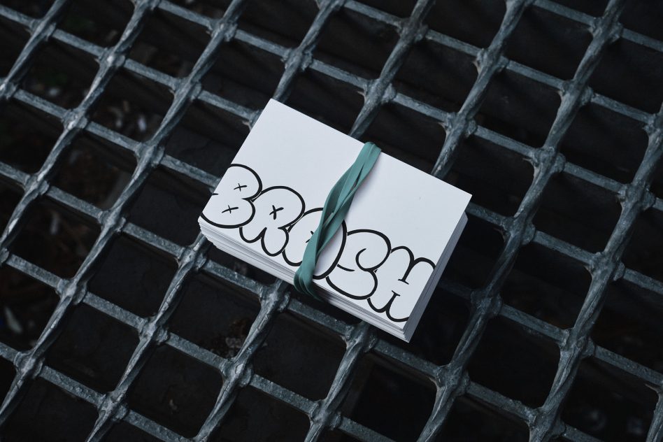 Bundle of business cards with graffiti-style text on metal grid background. Ideal for designers needing creative fonts and mockups for urban-themed projects.